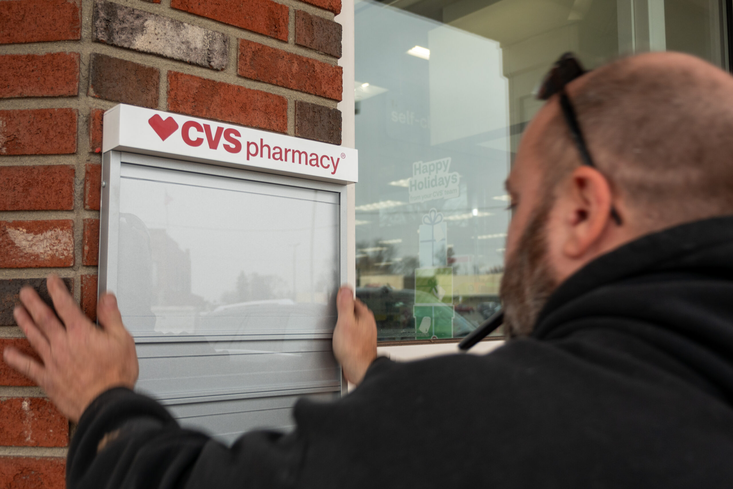 An Identiti vendor installing a small plaque on a CVS retail location's exterior wall.