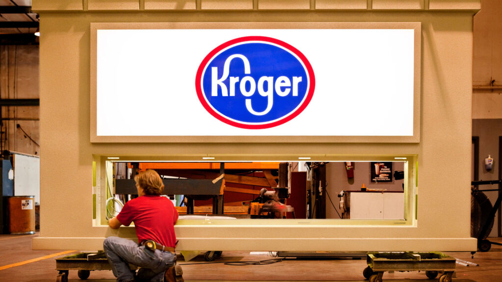 An Identiti manufacturing employee works on a large Kroger monument sign.