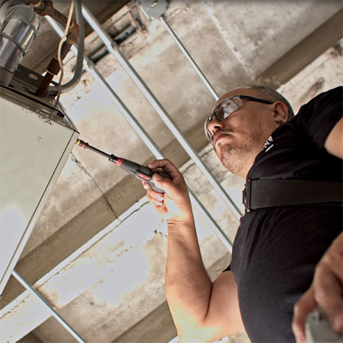 An Identiti facilities professional working on a location's HVAC system.