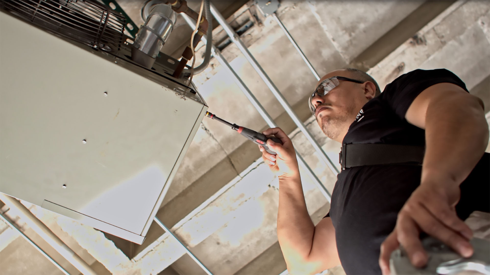 An Identiti maintenance professional working on an overhead HVAC system.