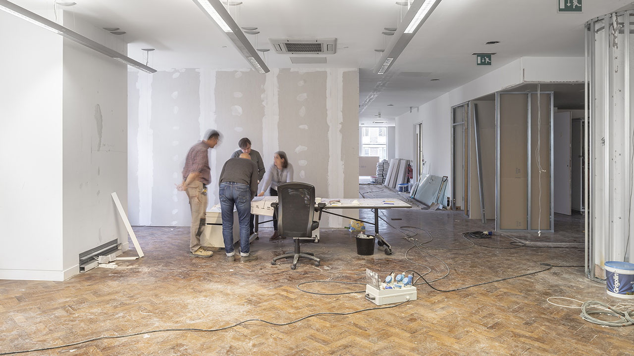 A group of Identiti facility partners around a table in a room being actively remodeled.