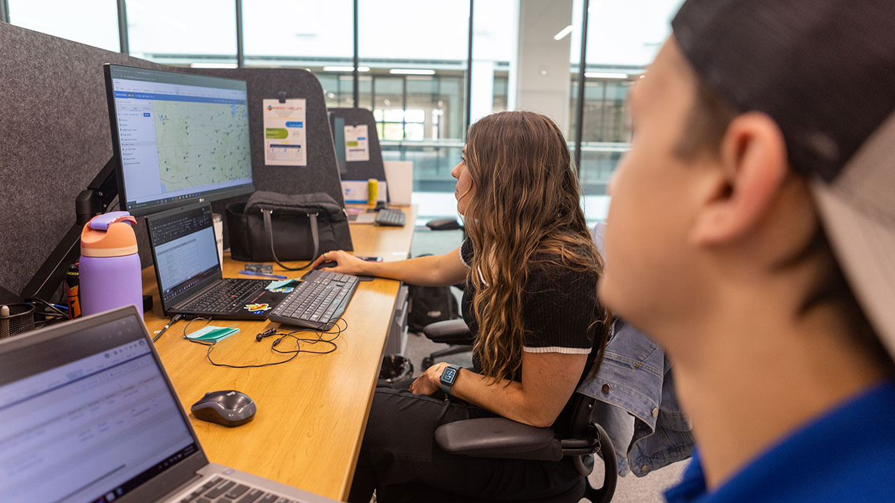 Two Identiti team members work together on a laptop computer.