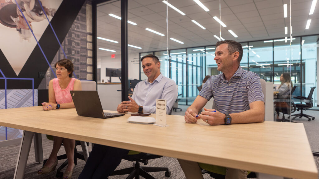 Three Identiti leaders in a meeting behind a conference table.