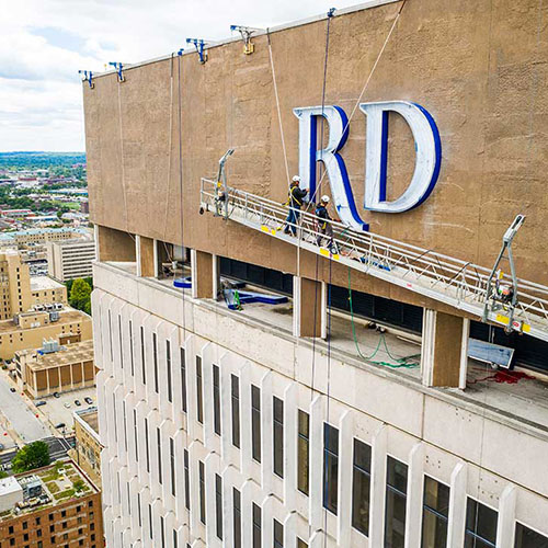 Identiti vendors installing a large illuminated building sign for Baird.