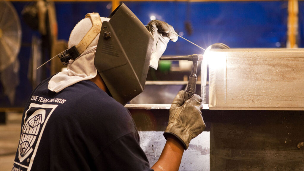 An Identiti manufacturing team member welding a new sign component.