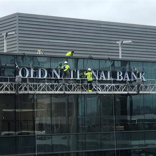 Multiple Identiti installation partners atop a skyscraper, installing new signage for Old National Bank.