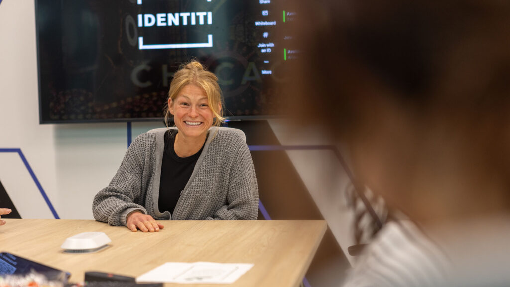 A smiling Identiti team member sitting across a conference table.