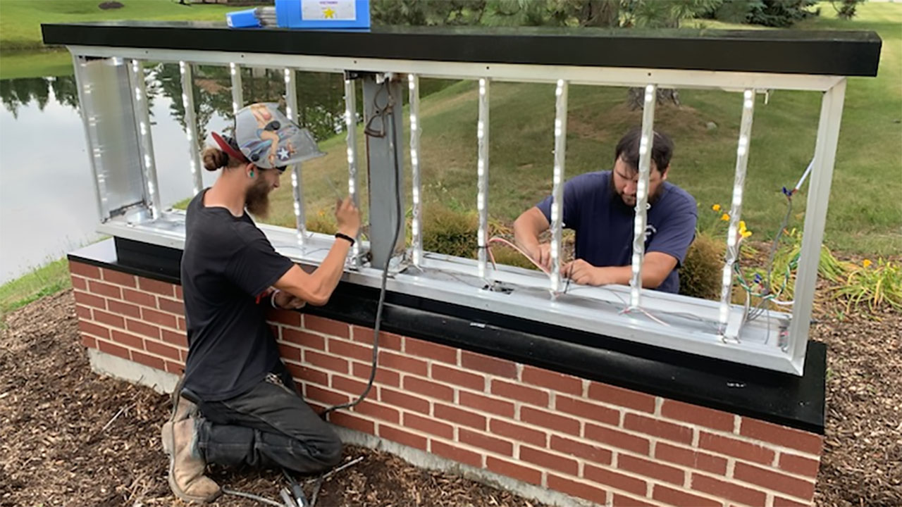 Two Identiti team members completing electrical work on an exterior monument sign.