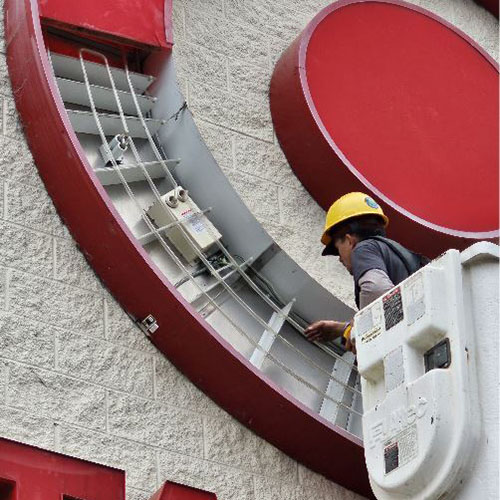 A maintenance worker inspects the lighting elements inside a large Target retail store sign.